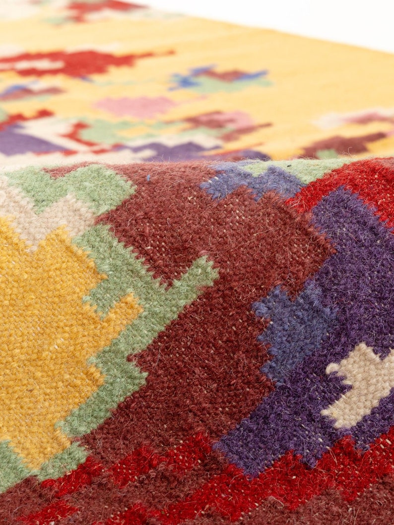 K&ouml;nnte beinhalten: Nahaufnahme eines bunten gewebten Teppichs mit geometrischem Muster. Der Teppich ist aus Wolle und hat eine Vielzahl von Farben, darunter Rot, Gelb, Gr&uuml;n, Blau und Wei&szlig;.