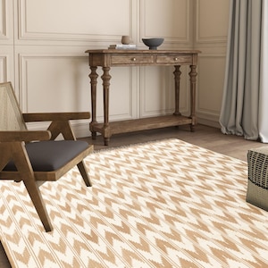 May include: A white and brown patterned rug with a chevron design. The rug is in a living room setting with a wooden console table and a chair.