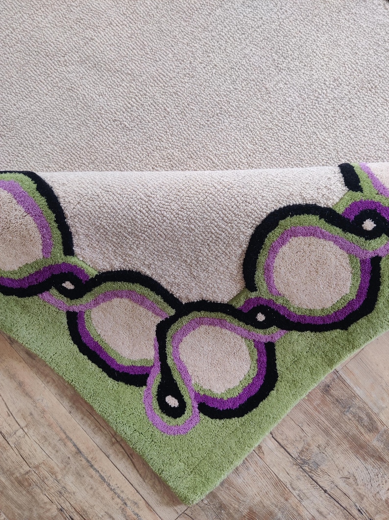 Hand tufted wool rug with green border and purple chain pattern on neutral background, modern designer area rug for living room or bedroom