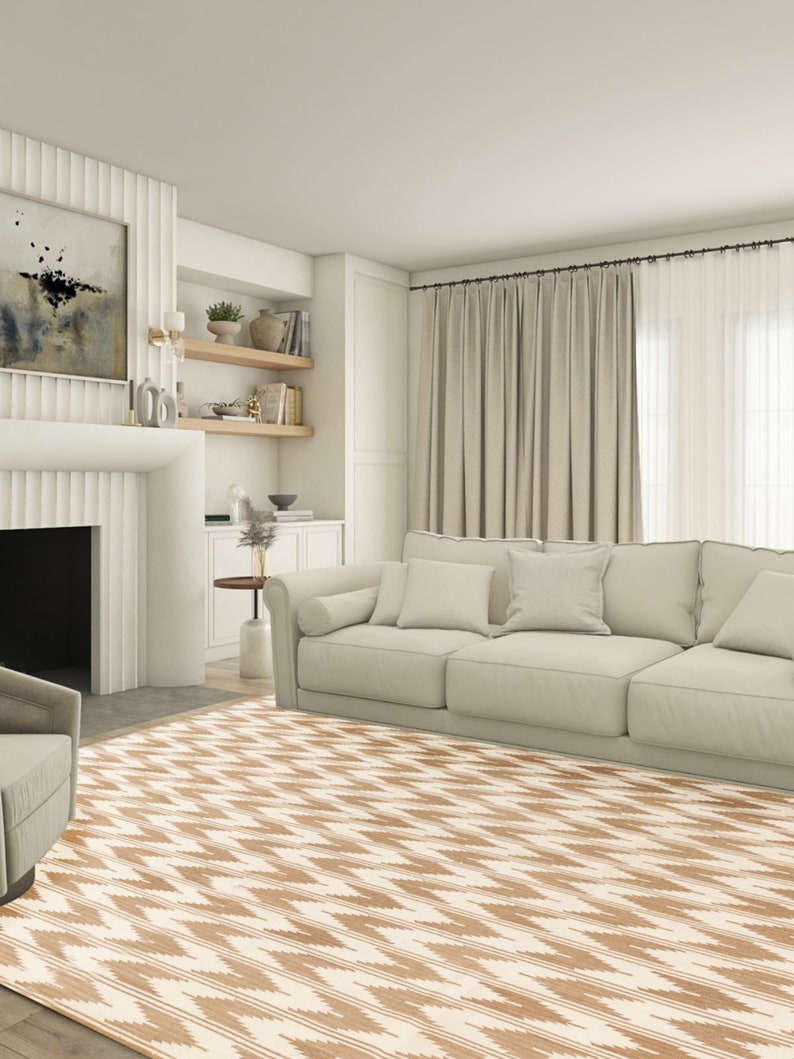 Puede incluir: Una alfombra de &aacute;rea beige y blanca con un dise&ntilde;o geom&eacute;trico. La alfombra est&aacute; en una sala de estar con un sof&aacute; blanco y cortinas.