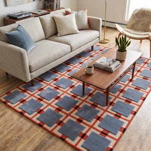 May include: A rectangular area rug featuring a grid pattern of raised blue squares set against a cream background with intersecting orange and black lines. The rug has a textured, multi-dimensional surface with a repeating geometric design.