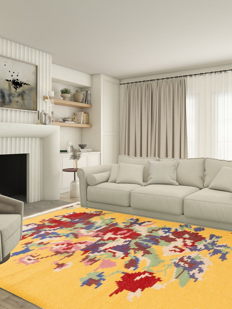 K&ouml;nnte beinhalten: Ein gelber Teppich mit einem farbenfrohen, abstrakten Muster. Der Teppich befindet sich in einem Wohnzimmer mit einem wei&szlig;en Sofa und einem Kamin.