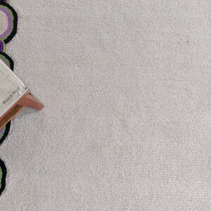 Hand tufted wool rug with green border and purple chain pattern on neutral background, modern designer area rug for living room or bedroom