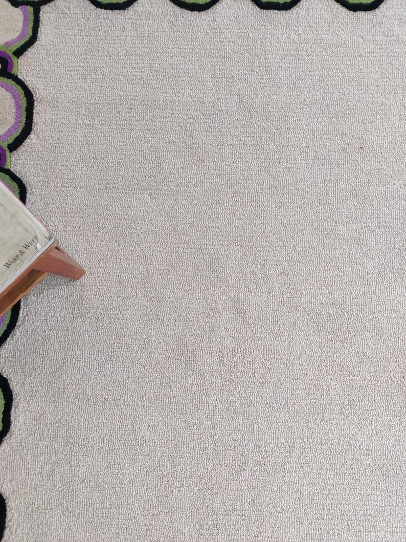 Hand tufted wool rug with green border and purple chain pattern on neutral background, modern designer area rug for living room or bedroom