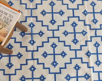 Puede incluir: Una alfombra blanca con un patrón geométrico azul. El patrón está formado por cuadrados y cruces. La alfombra está hecha de algodón y es perfecta para añadir un toque de estilo a cualquier habitación.