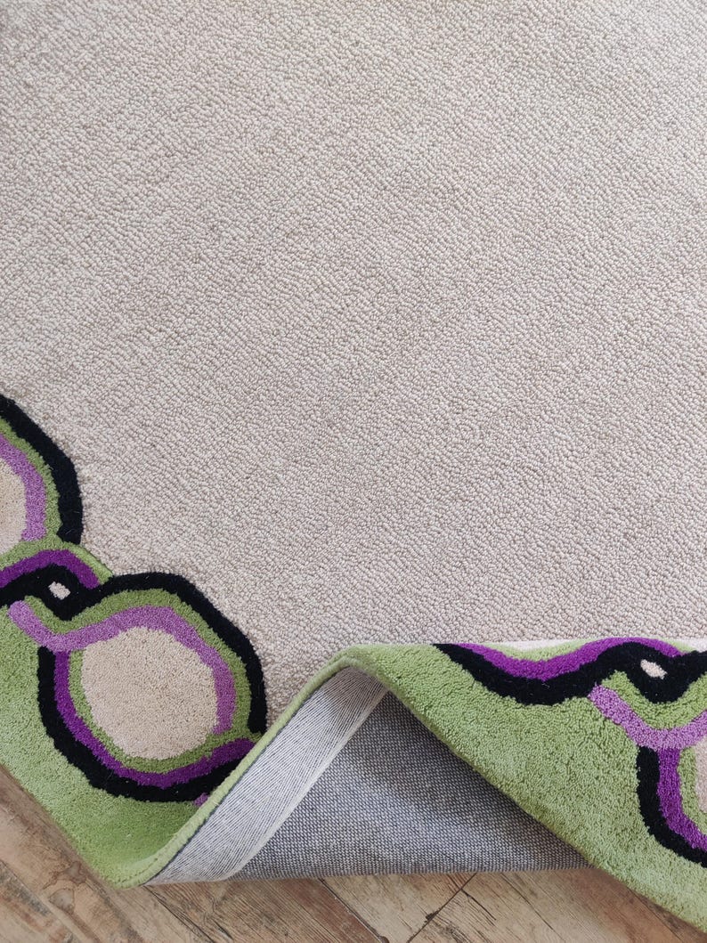 Hand tufted wool rug with green border and purple chain pattern on neutral background, modern designer area rug for living room or bedroom