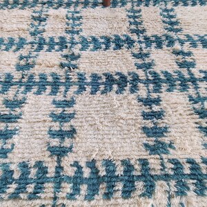 May include: A white and teal blue shag rug with a geometric pattern. The rug has a soft, fluffy texture.