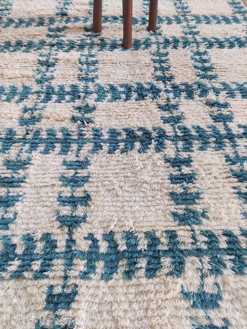 May include: A white and teal blue shag rug with a geometric pattern. The rug has a soft, fluffy texture.