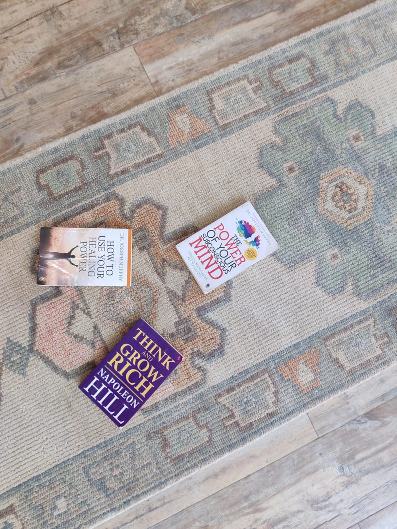 May include: Three self-help books on a beige rug with a blue and orange pattern. The books are titled "Think and Grow Rich" by Napoleon Hill, "How to Use Your Healing Power" by Dr. Joseph Murphy, and "The Power of Your Subconscious Mind" by Dr. Joseph Murphy.