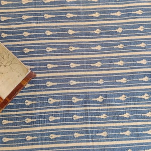 Op de afbeelding: Een blauw en wit gestreept tapijt met een subtiel patroon van witte pijlen. Het tapijt heeft een zachte, textuur en is perfect om elke kamer een vleugje stijl te geven.