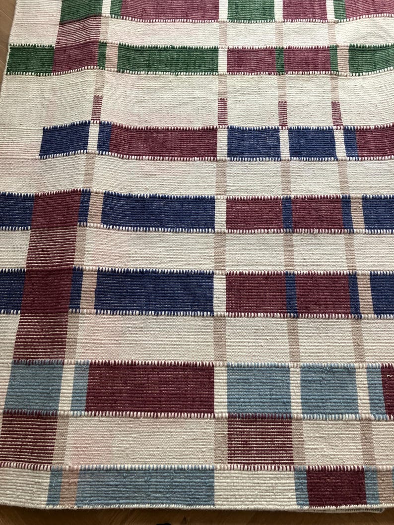 Puede incluir: Una alfombra tejida con un patr&oacute;n de cuadros en tonos de rojo, azul, verde y blanco.
