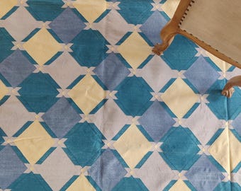 Puede incluir: Una alfombra con estampado de rombos azules, amarillos y grises. La alfombra tiene un diseño geométrico con un patrón repetitivo de rombos.