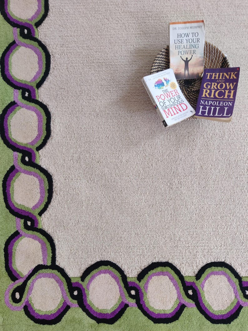 Hand tufted wool rug with green border and purple chain pattern on neutral background, modern designer area rug for living room or bedroom