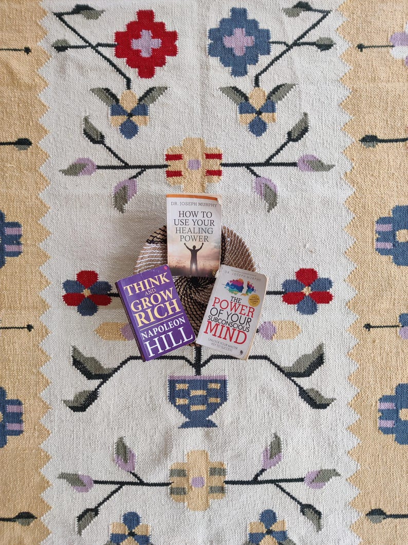 handwoven wool rug features a floral tribal kilim design with soft beige, red, blue, and pastel tones. Made from premium natural wool, this flatweave rug is durable, eco-friendly, and perfect for living rooms, bedrooms, or boho home décor. Each rug is handcrafted by skilled artisans, making it a unique and timeless piece for modern and traditional interiors.