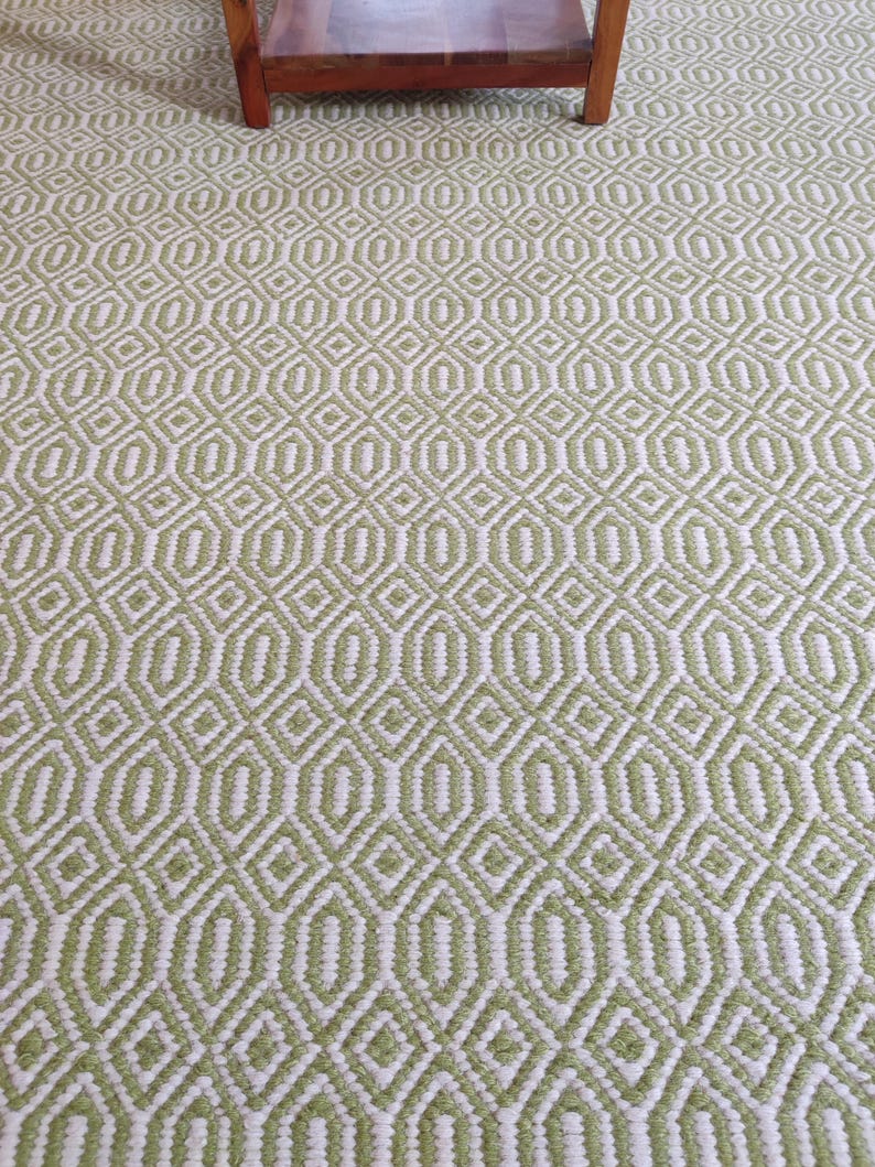 May include: A green and white patterned rug with a geometric design. The rug has a subtle sheen and a soft texture.
