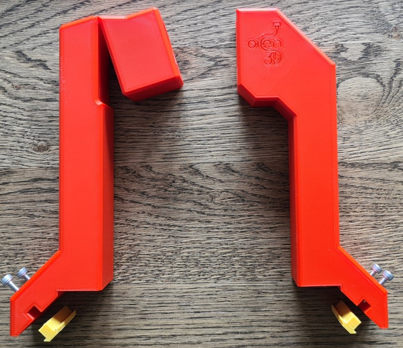 May include: Two red plastic 3D printed corner braces with a yellow plastic piece on the bottom of each brace. The brace on the right has the text "open 3D" printed on it.