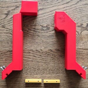 May include: Two red 3D printed plastic brackets with two yellow plastic spacers. The brackets have a logo that says "Open 3D".