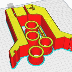May include: A 3D printed red and yellow object with three cylindrical holes. The object is designed to hold multiple items.