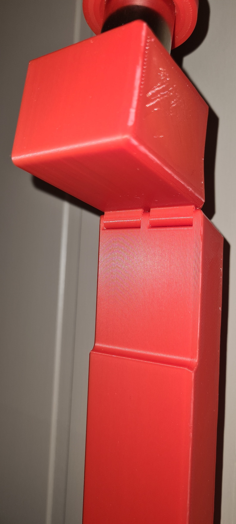 May include: A red 3D printed object with a hinged lid. The object is made up of two rectangular boxes stacked on top of each other.