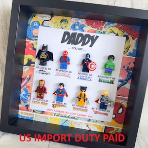 May include: A framed artwork with Lego superhero figures, such as Batman, Spider-Man, and Captain America, set against a comic book backdrop. The artwork includes the text "DADDY... You Are..." and comparisons to superheroes. A Father's Day message is also present.