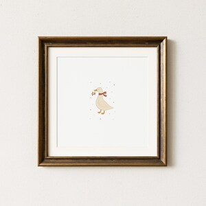 May include: A framed print featuring a whimsical illustration of a goose. The goose is depicted in a soft beige color, wearing a red scarf and holding berries in its beak. The artwork is set against a white background, framed in a dark brown wooden frame.