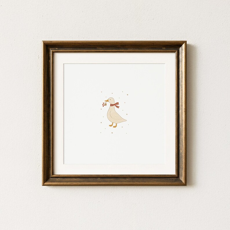May include: A framed print featuring a whimsical illustration of a goose. The goose is depicted in a soft beige color, wearing a red scarf and holding berries in its beak. The artwork is set against a white background, framed in a dark brown wooden frame.