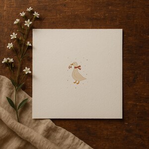 May include: A beige illustration of a duck wearing a red and white scarf, holding berries in its beak. The duck is on a cream-colored square, with small gray dots around it. A sprig of white flowers and a tan cloth are in the background.