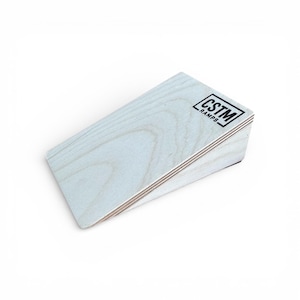 Puede incluir: Una rampa de madera de color claro con el texto "CSTM RAMPS" en un cuadro rectangular negro. La rampa está en ángulo, con una superficie lisa y de color claro y veta de madera visible. La rampa está diseñada para el skateboarding u otros deportes de acción.