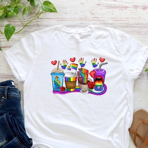 May include: White t-shirt with a graphic of rainbow-colored drinks, hearts, and handprints. The graphic includes the text "Love is Love".