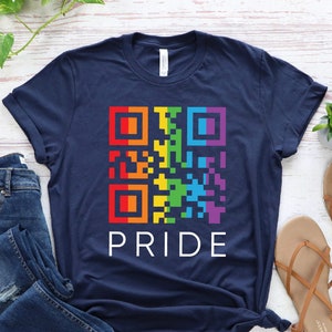 May include: A navy blue t-shirt with a rainbow colored QR code and the word "PRIDE" printed in white.