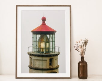 May include: A close-up of a lighthouse with a red roof and a glass lantern. The lighthouse is made of concrete and has a white exterior. The lantern is lit and shining brightly.