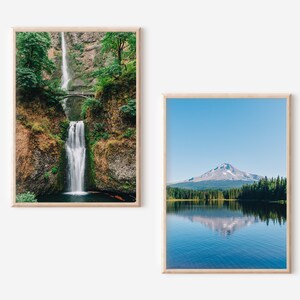 May include: Two framed landscape photographs. The first shows a waterfall cascading down a rocky cliffside with lush green foliage. The second shows a mountain reflected in a still lake with a blue sky and green trees.