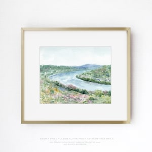 May include: A landscape watercolor painting featuring a winding river flowing through a valley with green hills and soft pink foliage in the foreground, enclosed in a thin gold-colored rectangular frame with a white mat border.