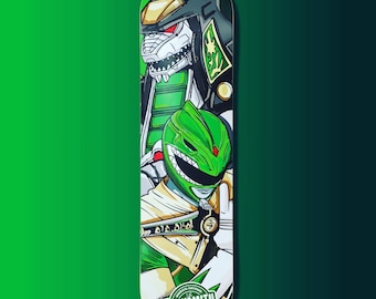 Puede incluir: Un Power Ranger verde y un monstruo verde y negro con la cara blanca aparecen en una tabla de skate. La tabla es negra con un logotipo blanco que dice "The Decksmith" en un círculo verde.