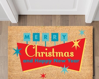 May include: A brown coir doormat with the text "Merry Christmas and Happy New Year" in a retro style with red, yellow, and blue accents. The text is surrounded by stars.