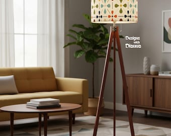 May include: A floor lamp with a dark wood tripod base and a cylindrical fabric shade featuring a repeating floral pattern in red, yellow, teal, and dark blue. The text "Designs with Dianna" is visible on the right side of the lamp shade.