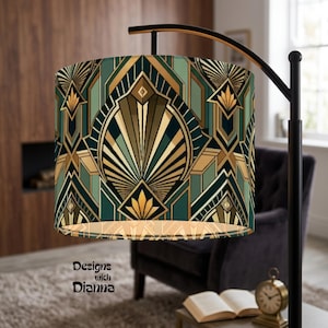 May include: A cylindrical lamp shade featuring a geometric pattern in shades of dark green, teal, and gold. The design consists of repeating fan-like shapes and angular lines. The text "Designs with Dianna" is printed in black on the lower left side.