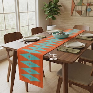 May include: A rectangular table runner featuring a vibrant orange background with a repeating pattern of teal diamond shapes, each containing a small orange starburst. The text "Designs with Dianna" is printed in white on the runner surface.