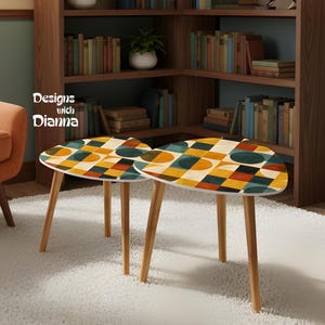 May include: Two nesting tables with three light wood legs each and triangular tops featuring a geometric pattern of squares and circles in shades of mustard yellow, dark teal, and black. The text Designs with Dianna is visible on the left.