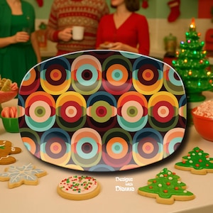 May include: Oval serving platter with a retro design of colorful concentric circles in shades of orange, yellow, green, and blue. The platter is surrounded by Christmas cookies and a small Christmas tree.