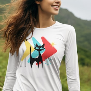 May include: White long-sleeve shirt with a black cat graphic and colorful geometric shapes. The cat has blue eyes and a long tail.