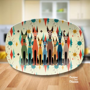 May include: An oval serving platter with a retro design featuring stylized dogs in various colors. The dogs are arranged in a row against a cream background with geometric shapes. The platter has a wooden surface.