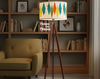May include: A floor lamp with a tripod wooden base and a cylindrical lampshade featuring a pattern of teal, orange, and yellow diamonds with black starburst accents. The text Designs with Dianna is printed on the side of the lampshade.