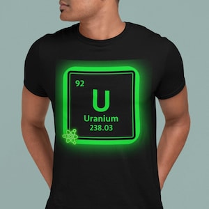 May include: Black t-shirt featuring a glowing green square with the element symbol for Uranium. The square contains the number 92, the letter "U", the word "Uranium", and the atomic mass 238.03. A small atom graphic is in the lower left corner.