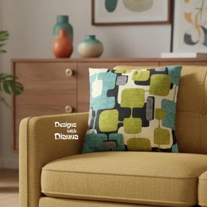 May include: A square throw pillow featuring a geometric pattern of rounded squares in shades of lime green, teal, and gray on a cream background. The text "Designs with Dianna" is printed in white on the left side of the pillow cover.