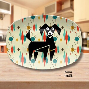 May include: An oval serving platter with a retro design. The platter features a black dog illustration on a cream background with a pattern of colorful diamonds and starbursts. The words "Designs with Dianna" are printed on the bottom right.
