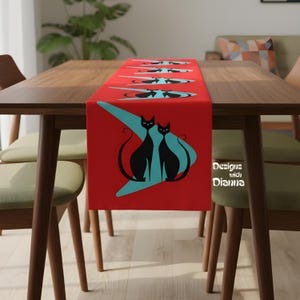 May include: A red table runner featuring a retro design with black cat silhouettes and teal accents. The runner is placed on a wooden table, creating a striking contrast. The text "Designs with Dianna" is visible on the right side.