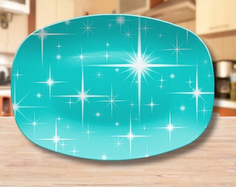 May include: An oval-shaped serving platter in a bright turquoise color featuring a repeating pattern of white four-pointed stars and smaller sparkles distributed across the entire surface of the dish.
