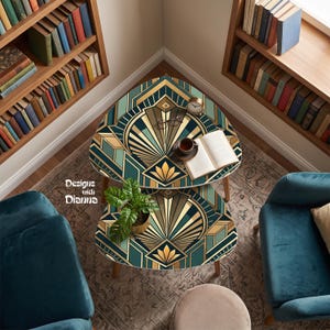 May include: Two nested triangular tables featuring a geometric art deco pattern in teal, gold, and dark brown. The top table holds an open book, a small clock, and eyeglasses. The text Designs with Dianna is visible on the left side.