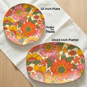 Puede incluir: Un plato redondo de 25 cm y una fuente rectangular de 25x36 cm con un dise&ntilde;o floral retro. Los platos crema presentan flores naranjas, rosas, amarillas y verdes. El texto "Designs with Dianna" es visible.